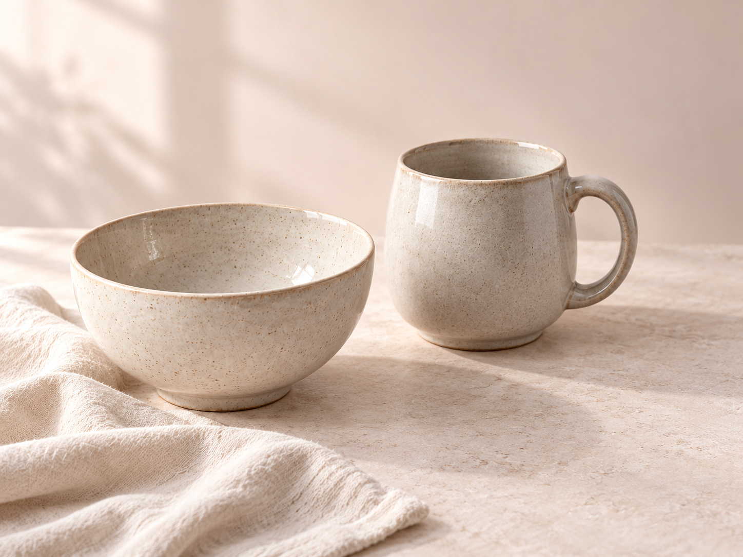 Oat ceramic bowl and ash mug with a soft linen cloth on a pale stone surface